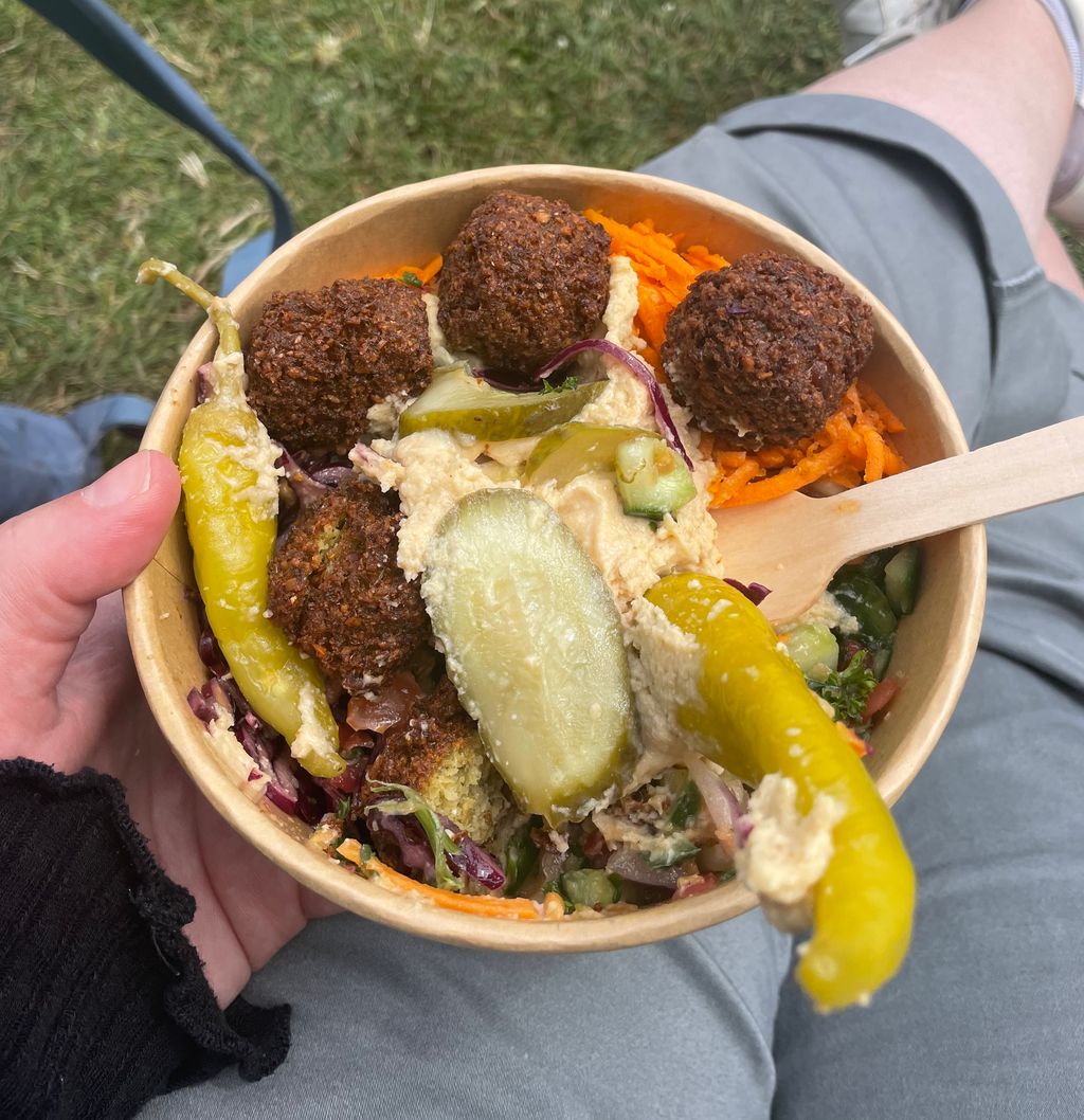 A salad bowl topped with falafels, gherkins and chillis