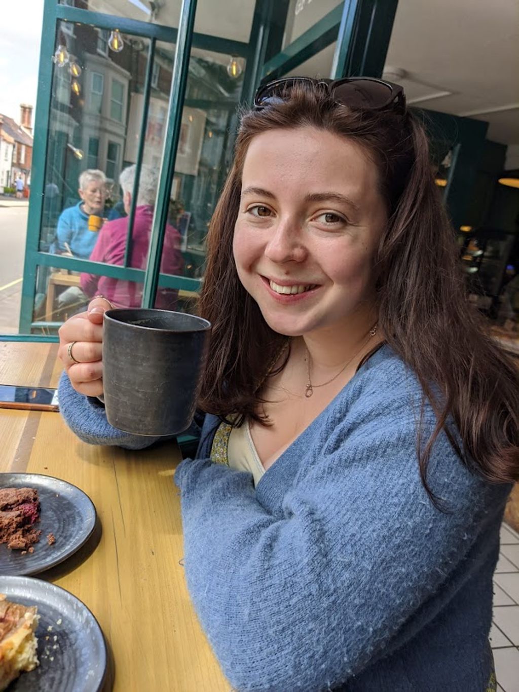 Holly drinking a coffee and enjoying a raspberry chocolate brownie